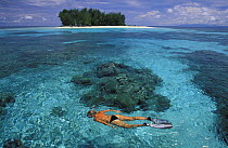 Snorkeling in clear waters infront of the small and uninhabited island of Dondola, Togian Islands, Sulawesi, Indonesia. Model released.