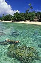 Woman snorkeling over some healthy coral boulders off Walea Island, Togian Islands, Sulawesi. Model released.