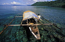 Local fishing boat over coral reef, Walea island, Sulawesi, Indonesia.