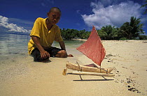Baju / sea gypsy boy, playing with home made boat at waters edge. Sulawesi, Indonesia.