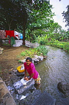 Woman washing clothes in river, Mauritius.