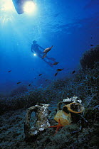 Person diving with ancient amphora, probably from Roman age, Giglio, Italy. Model released.