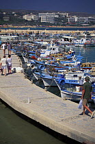 Tourists and fishing boats in a small harbour just outside Aya Napa, Cyprus.