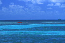 Person wading beside kayak in clear waters, Belize. Model and Property Released.
