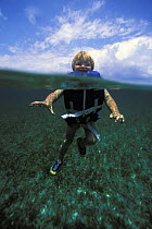 Young boy in a life-jacket swimming in the sea, Belize. Model released.