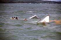 Crew of a sinking Sonar have activated an orange flare and wait to be rescued after their keelboat was overcome by waves during racing at Cowes Week, UK, 2001.