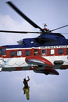 Coastguard helicopter hoists a crewman up to safety.