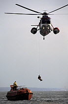 Coastguard helicopter hoists a crewman up to safety from a ship's liferaft during a practise rescue.