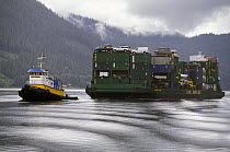 Tug towing a cargo of cars and vans through the Tongass National Forest, south east Alaska.
