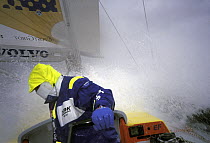 Crew member aboard "EF Language" faces away from the spray on the deck in the Southern Ocean during the Whitbread Round the World Race, 1997-1998.