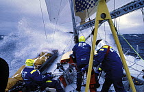 Wave rushes through the crew on deck of "Team EF" in the Whitbread Round the World Race, 1997-1998.
