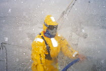 Helmsman on "Intrum Justitia" is geared up in waterproofs and goggles as they move through the Southern Ocean in the Whitbread Round the World Race, 1993.