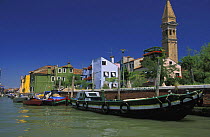 Canal on Burano Island. The leaning tower of the San Martino church is in the background, Italy.