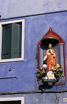 Statue of Jesuson the outside wall of a purple house, Burano, Italy.