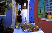 Chef with a display of the food offered at Trattoria Gatto Nero, Burano, Italy.