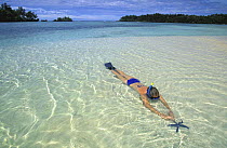 Snorkelling woman and blue sea star, Palau, Micronesia. Model released.