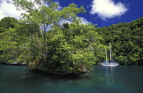 Sailing yacht anchored behind a small limestone island, Palau, Micronesia.