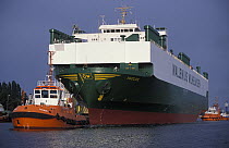 Two tugs assist a RoRo ocean transporter ship off the dock in Southampton, UK.