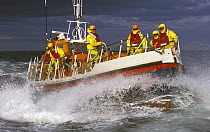 Crew of the Courtmacsherry, Ireland Lifeboat on the foredeck as she crashes through heavy seas. Designed to lie afloat at deep water moorings or at berth. The sheerline sweeps down for ease of survivo...