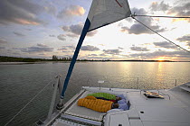 Children asleep at sunrise on the foredeck of a cruising catamaran, Bahamas. Model released.