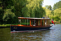 A classic river launch, "Merlin", cruising on the Norfolk Broads, England, UK.