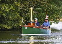 A classic steam boat gently cruising down a river, UK.