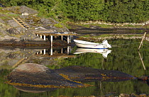 Small boat with outboard motor tied up to a jetty on the island of Lyr, on the west coast of Sweden