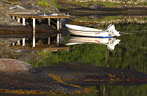 Small boat with outboard motor tied up to a jetty on the island of Lyr, on the west coast of Sweden.