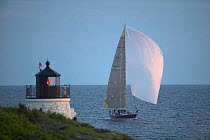 Yacht with spinnaker crossing the finish line of the Newport-Annapolis race at Castle Hill Light Newport, Rhode Island, USA.