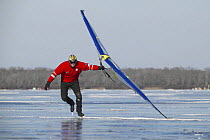 Man ice skating with a sail on Worden Pond, Rhode Island, USA.