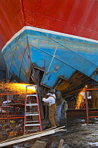 Workers cutting sheet metal on a trawler using a gas cutter.