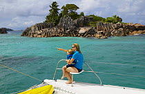 Mother and child pointing from the stern of a yacht. cruising in the Seychelles, Indian Ocean. Model released.