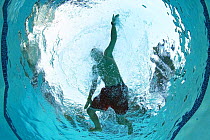 View from below of a boy swimming in a pool.