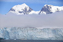 Beneath the low lying cloud, the 88ft sloop "Shaman" is dwarfed by Nordenskjold Glacier in Cumberland Bay, South Georgia. Property Released.