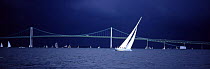 A thundery sky looming over the 12m Columbia during the Museum of Yachting's annual regatta with the Newport bridge in the background, Rhode Island, USA.