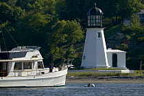 Grand Banks motoryacht moored off a small lighthouse on the east coast, USA.