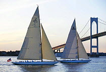 12m "Gleam" US11 and "Onawa" US6 sailing under the Newport Bridge at sunset, Rhode Island, USA.