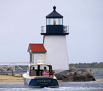 Small motorboat approaching a Nantucket lighthouse, USA.