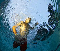 View from below of a young boy in a swimming pool.