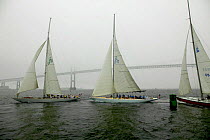 Three 12m yachts rounding the weather mark during a corporate charter on a foggy day in front of Newport Bridge, Rhode Island, USA.