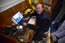Photographer Onne van der Wal onboard "Shaman", editing his digital images, anchored off South Georgia.