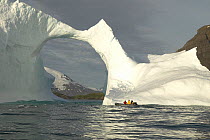 A yacht's tender taking a close-up look at a natural arch in an iceberg, south coast of South Georgia.