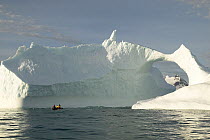 The crew of yacht "Shaman" in the yacht's tender, heading towards a natural arch in an iceberg, south coast of South Georgia. Model and Property Released.