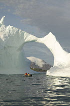 The crew of yacht "Shaman" in the yacht's tender, heading towards a natural arch in an iceberg, south coast of South Georgia. Model and Property Released.
