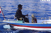 Gentleman in bowler hat at the helm of a classic wooden motor launch, Monaco Classic Week.