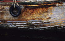 Rust-covered planks and peeling paint of an old wooden fishing boat under restoration in south Brittany, France.