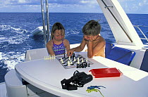 Children playing chess on board a boat. Model released.