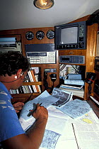Man reading weather charts at the chart table of a yacht.