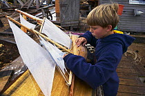 Young boy playing with a model sailboat in Vineyard Haven, Martha's Vineyard, Massachusetts, USA.