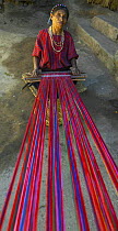 An old woman using a loom to hand weave traditional fabrics, Guatemala.